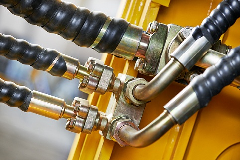 Close-up of interlocking metal gears coated in golden oil inside a gearbox. in operation inside industrial machinery