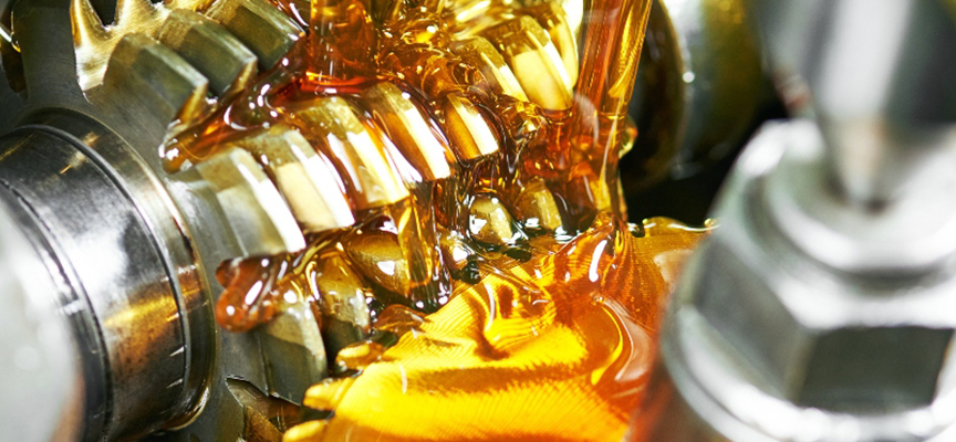 Close-up of interlocking metal gears coated in golden oil inside a gearbox. in operation inside industrial machinery
